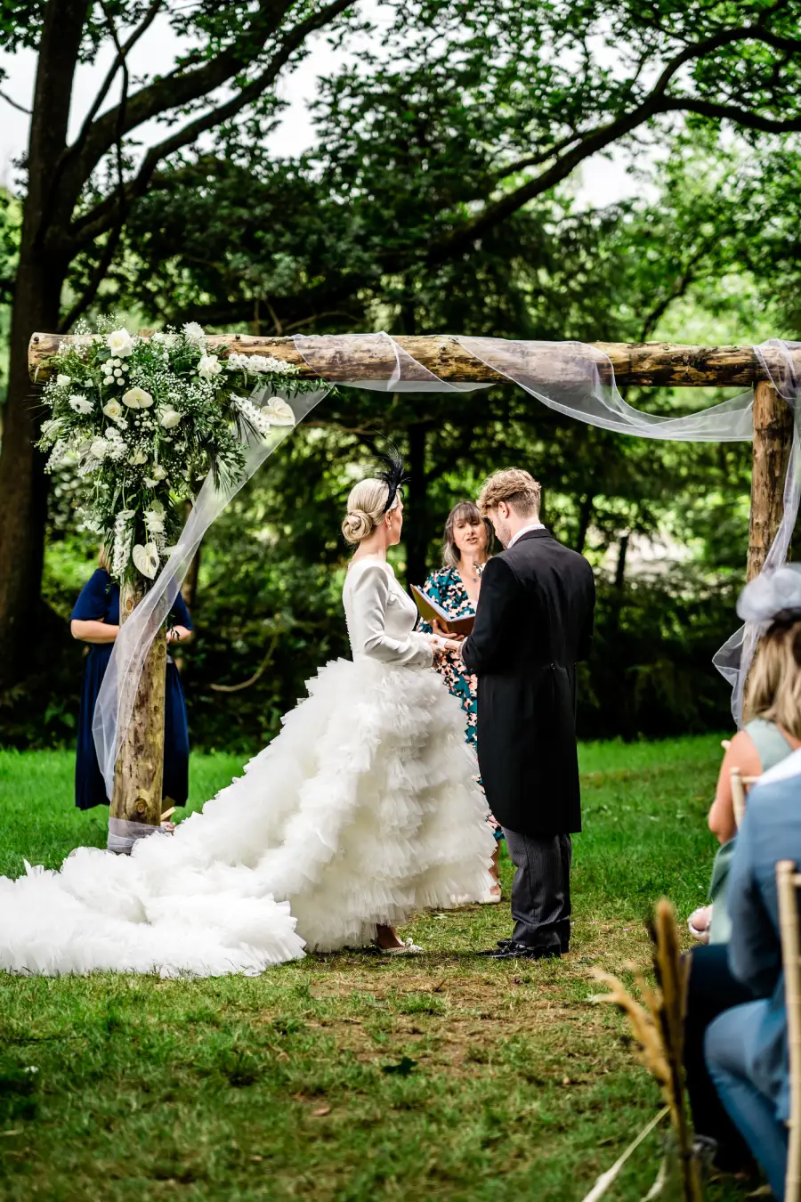 A bride and groom standing under a bespoke wooden arch at a humanist wedding officiated by Gower Celebrant.